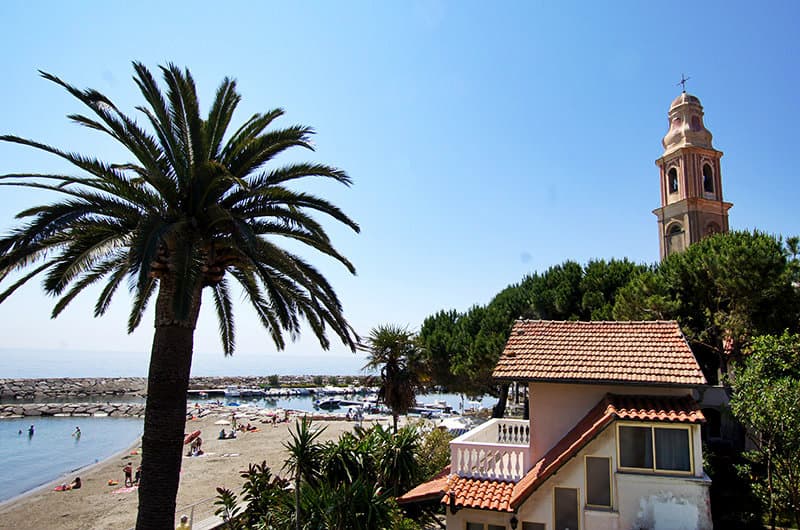 Une belle vue sur une Ã©glise, un palmier et la plage de sable de San Lorenzo al Mare