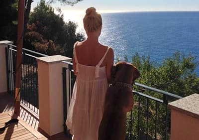 Un chien avec son propriétaire dans une terrasse en regardant la mer