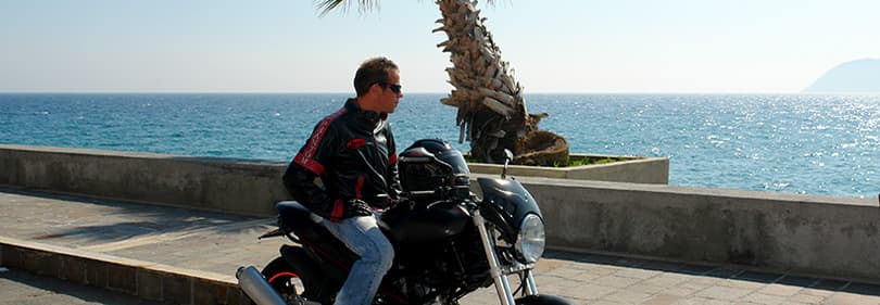Un homme avec une moto est à la recherche sur la mer en Ligurie